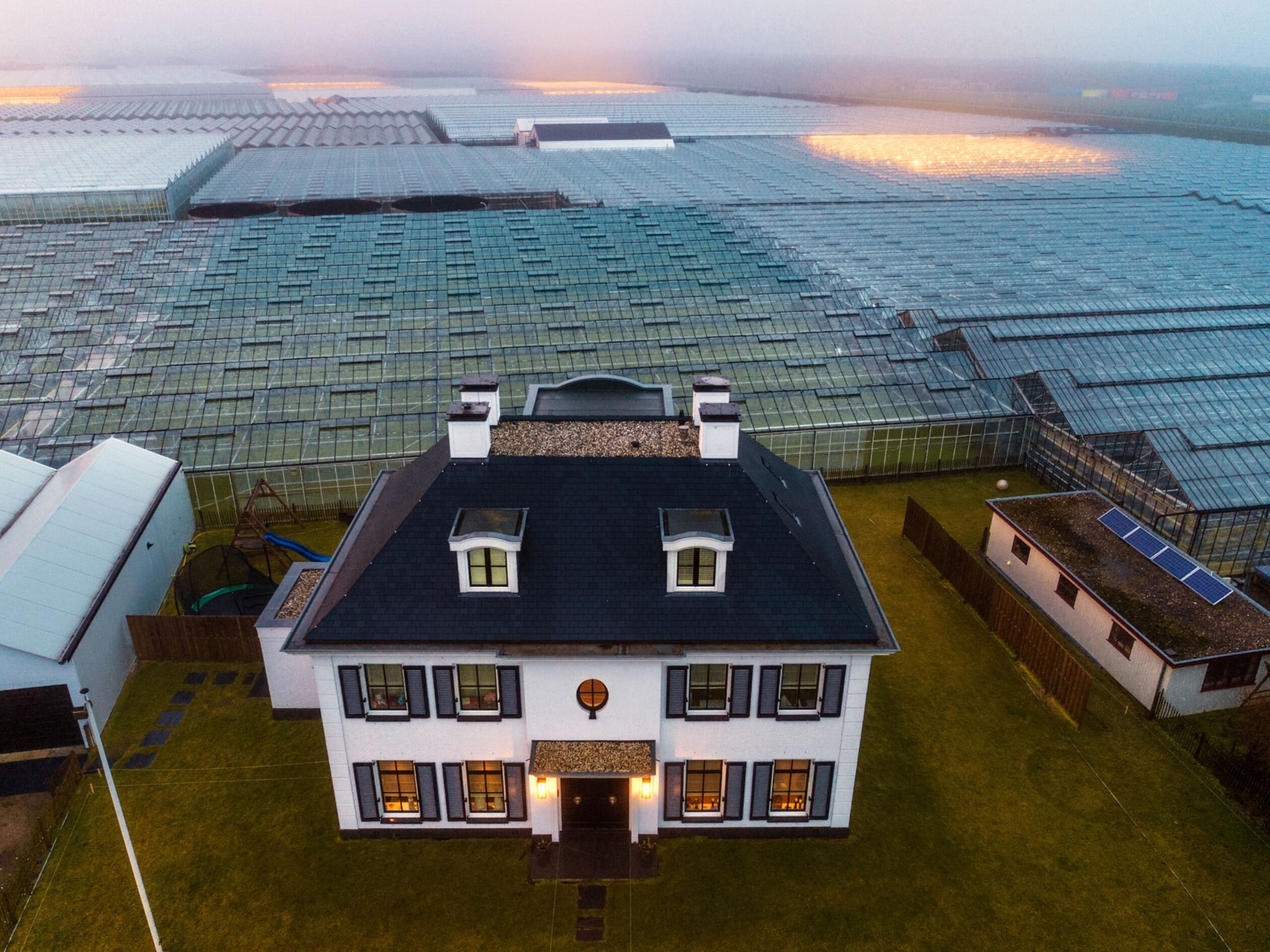 an aerial view of a farm house with greenhouses to the horizon